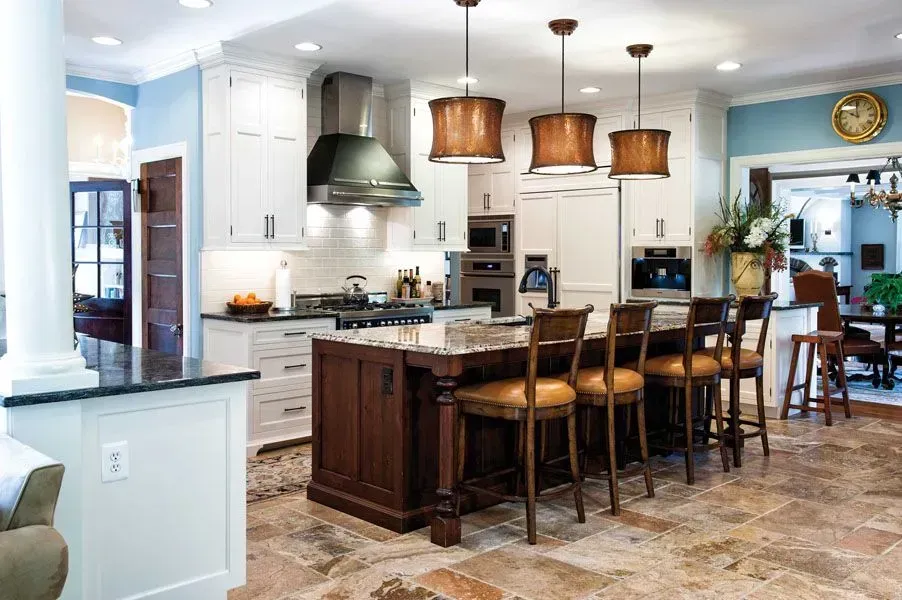 Elegant kitchen with island, bar stools, and pendant lights. White cabinetry, stainless steel appliances, and a blue wall.