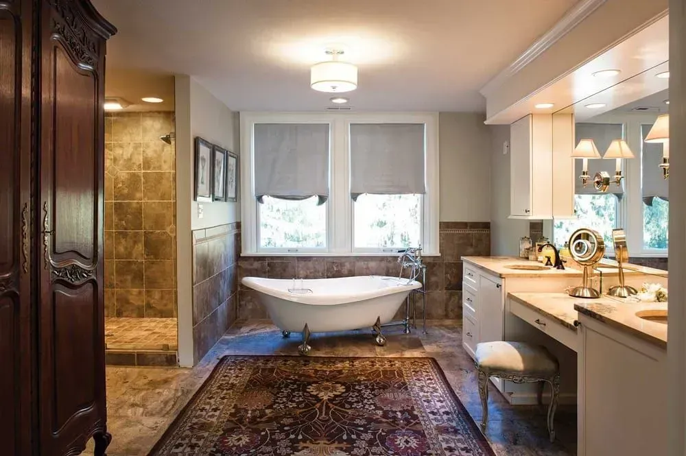 Luxurious bathroom with clawfoot tub, large rug, vanity, and walk-in shower.