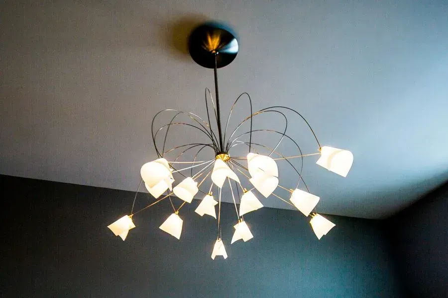 Modern chandelier with many lights, on a gray ceiling.