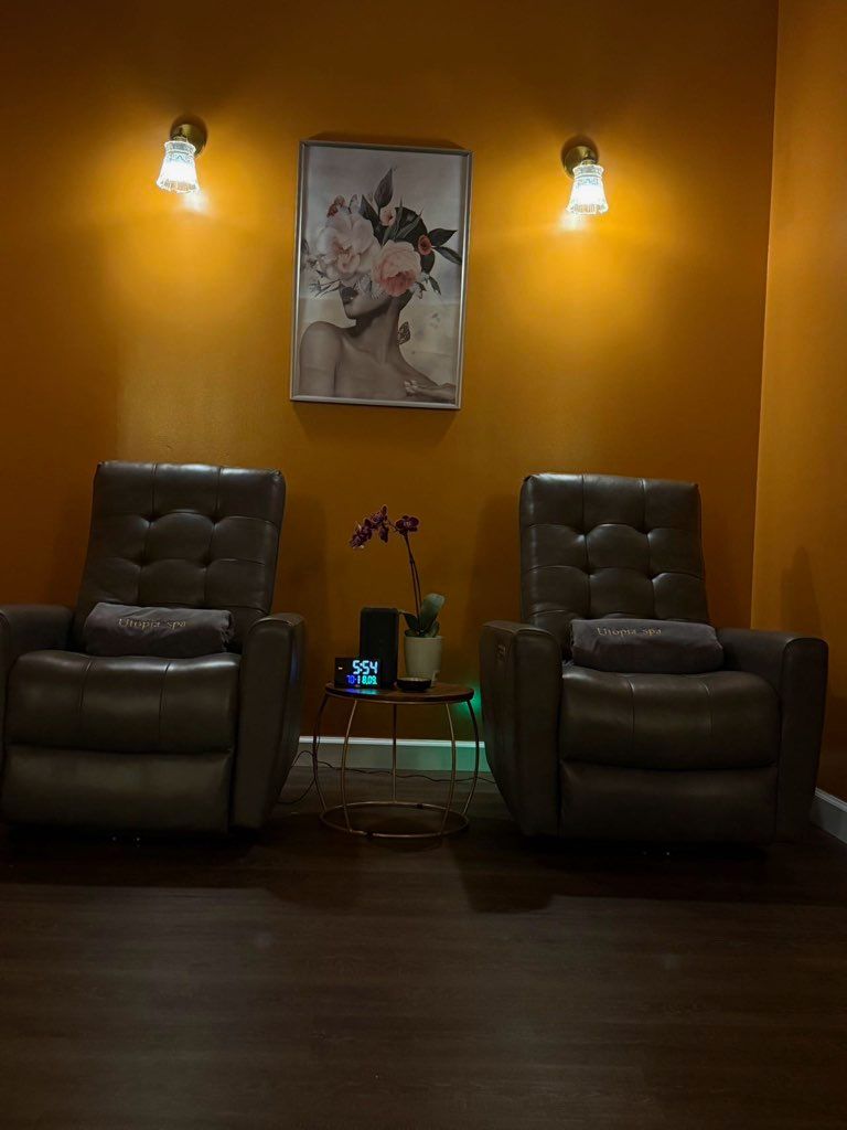 A room with two chairs , a table and a painting on the wall.