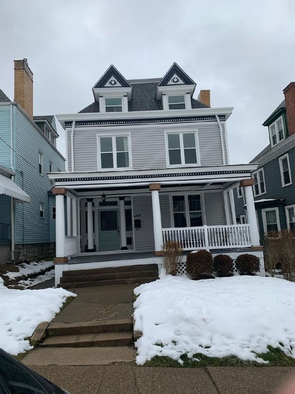 Two-story gray house with white trim, porch, and snow-covered ground.