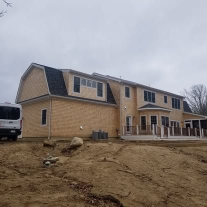 Two-story tan house under construction on a muddy lot with a white van parked beside it