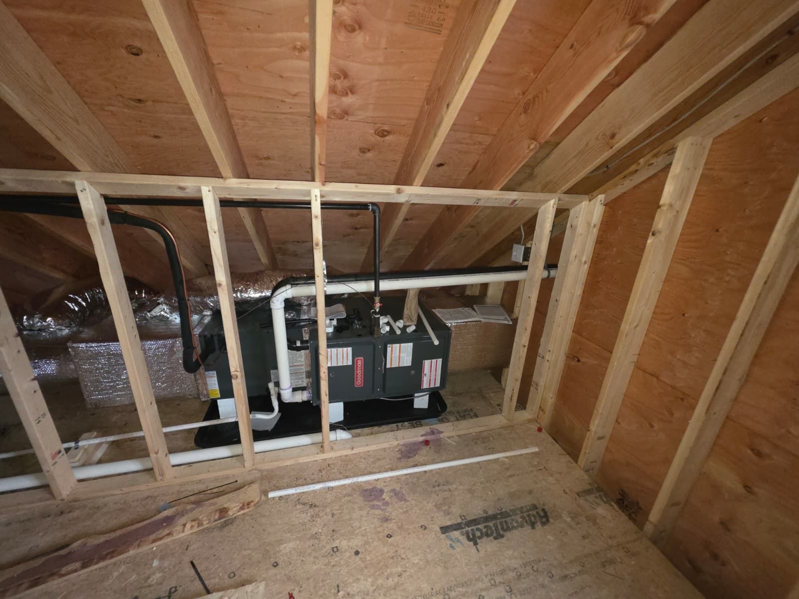 Attic with exposed wooden framing and HVAC equipment behind a wall opening