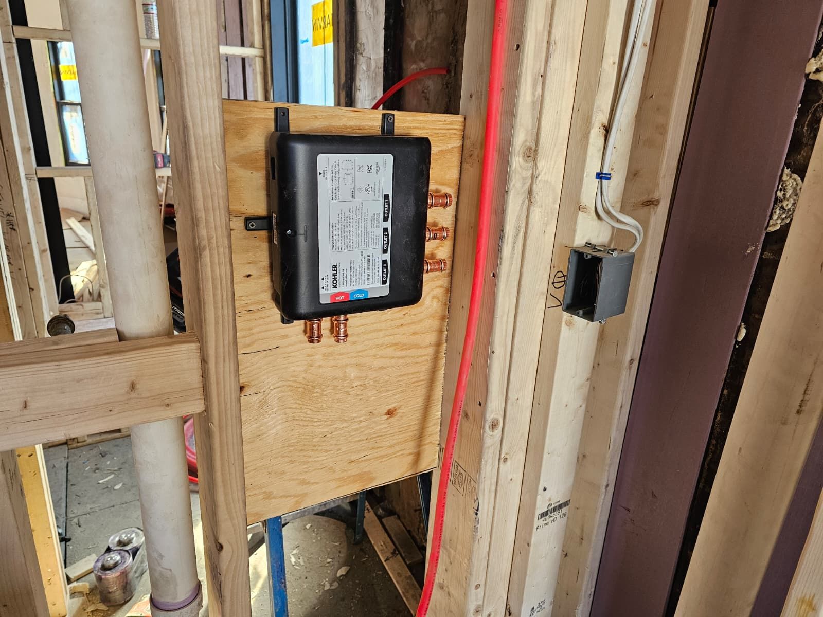 Electrical wiring and breaker panel mounted on unfinished wooden wall framing.