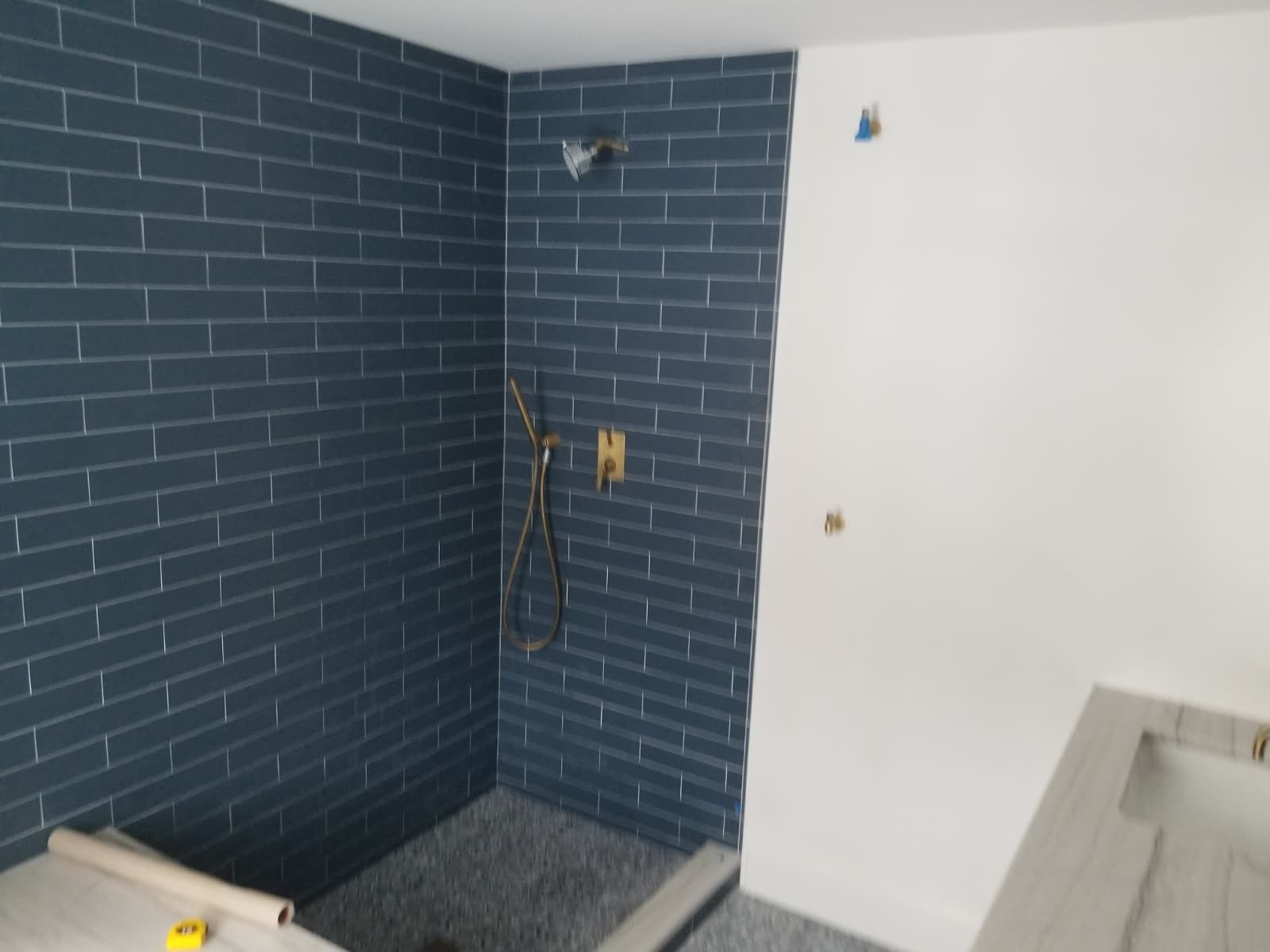 Small tiled utility corner with exposed wiring, a white wall, and a sink base on the right.
