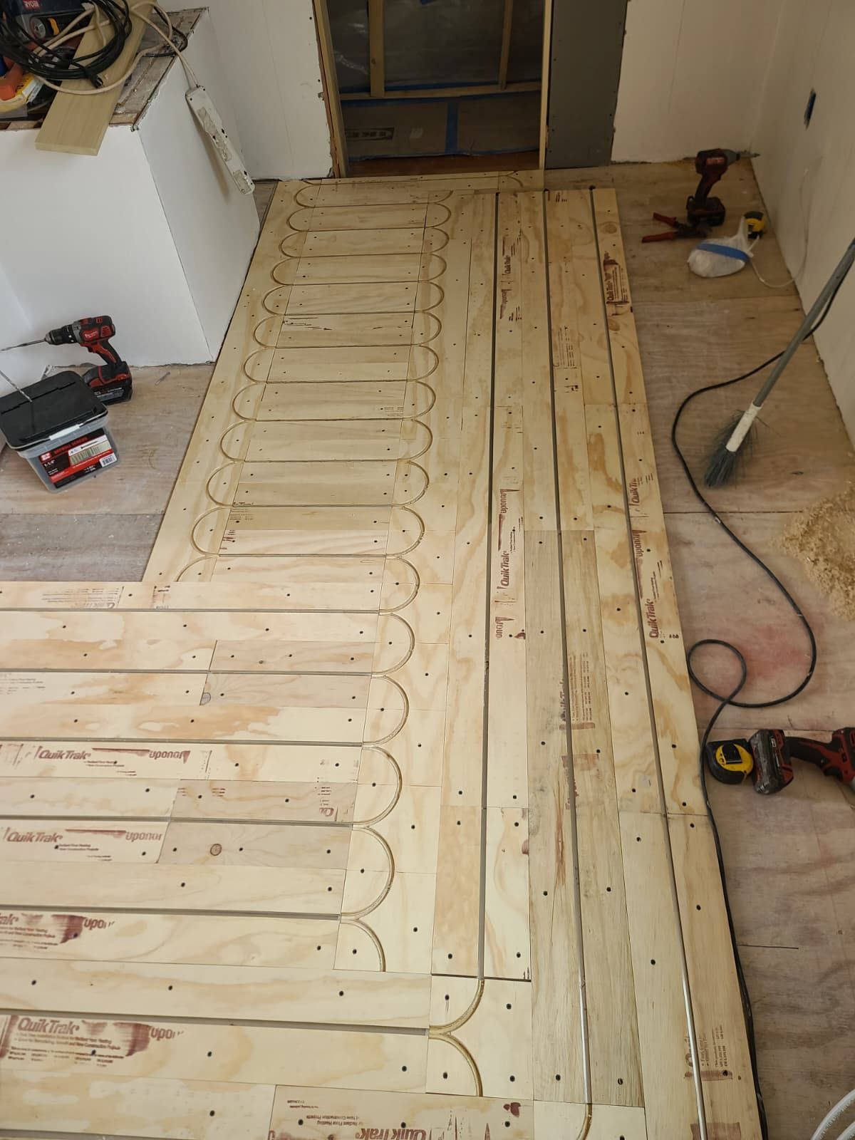 Wood subfloor with radiant heating tubing laid out in a room under renovation.