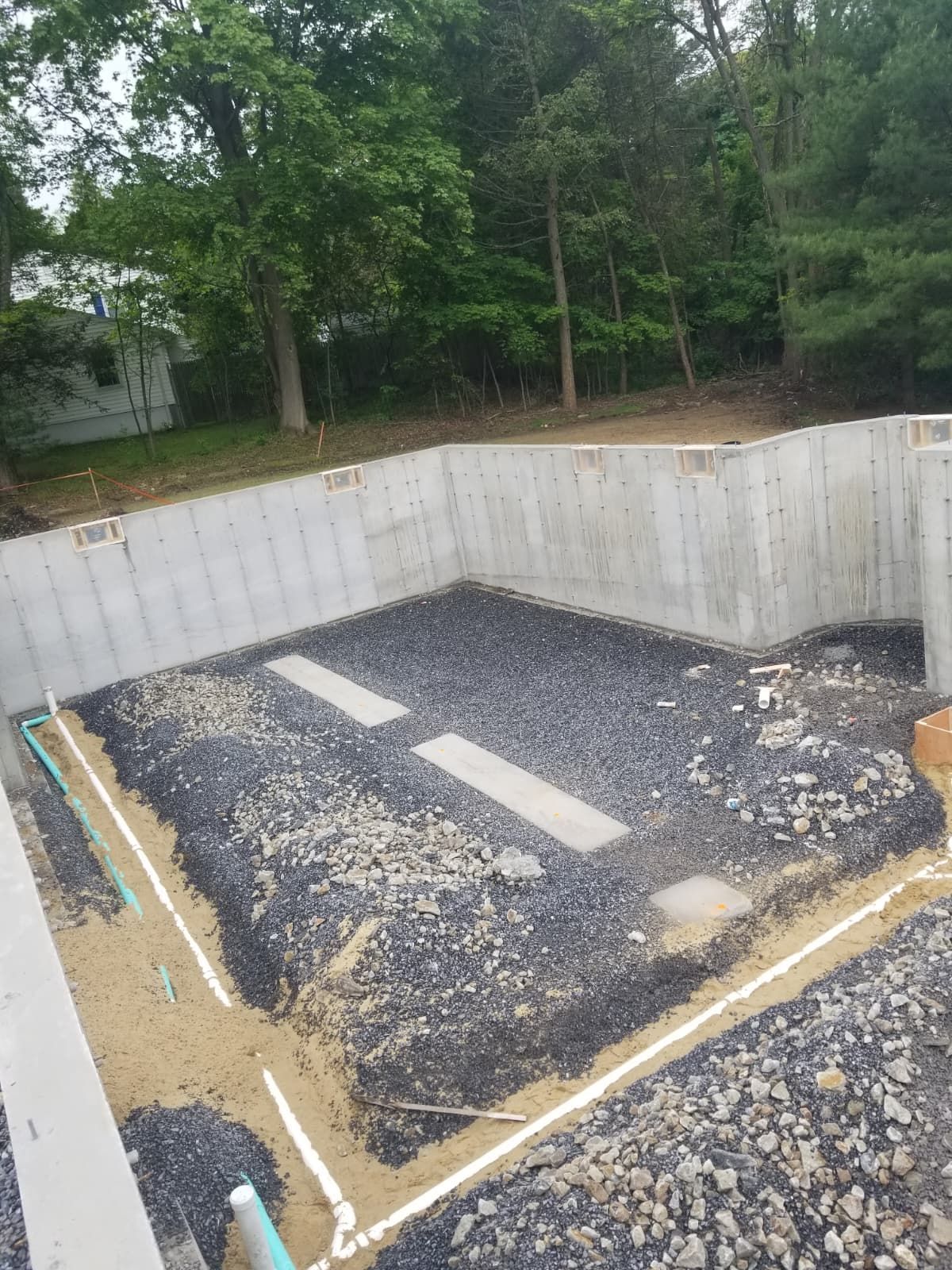 Small concrete pit with gravel and two white rectangles, bordered by wood and surrounded by trees.