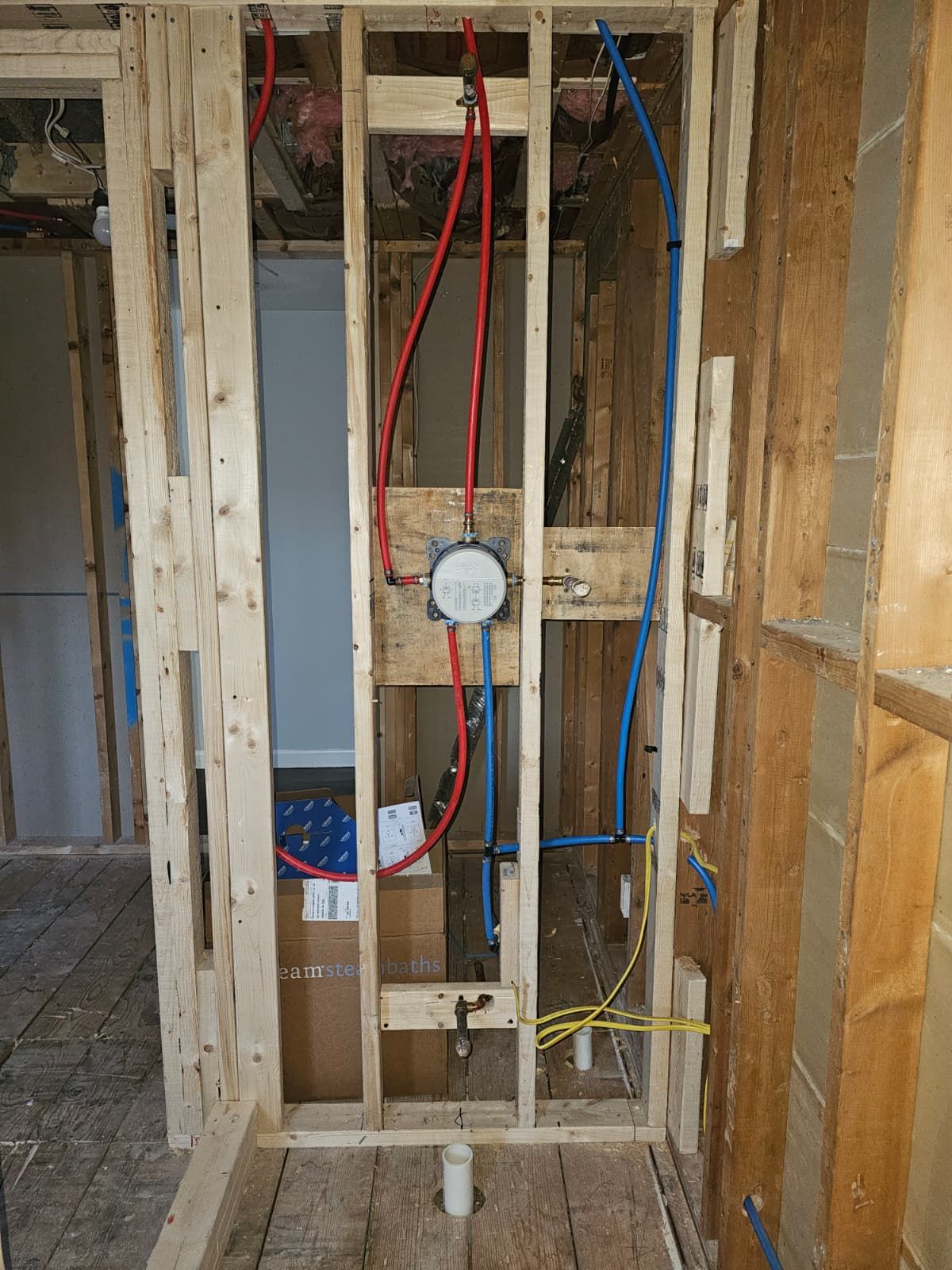 Exposed wall studs with electrical wiring and a round box in an unfinished interior renovation