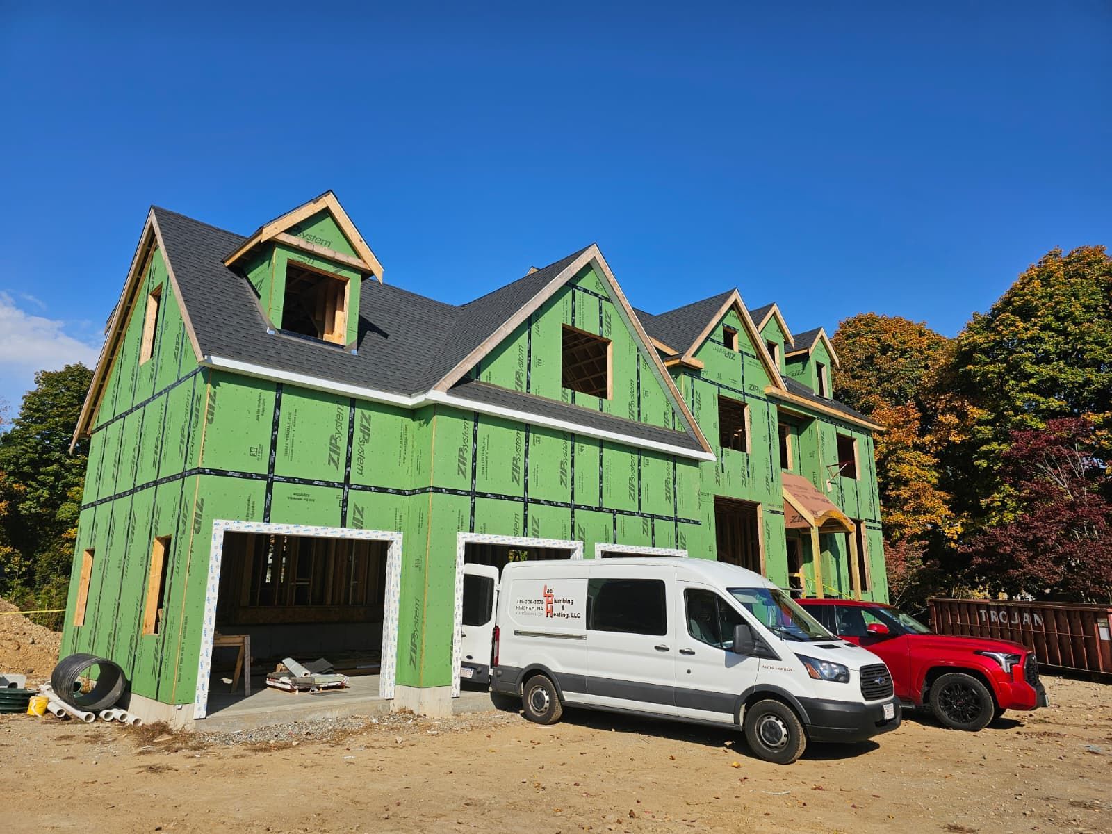 Green house under construction with white van and red car parked outside