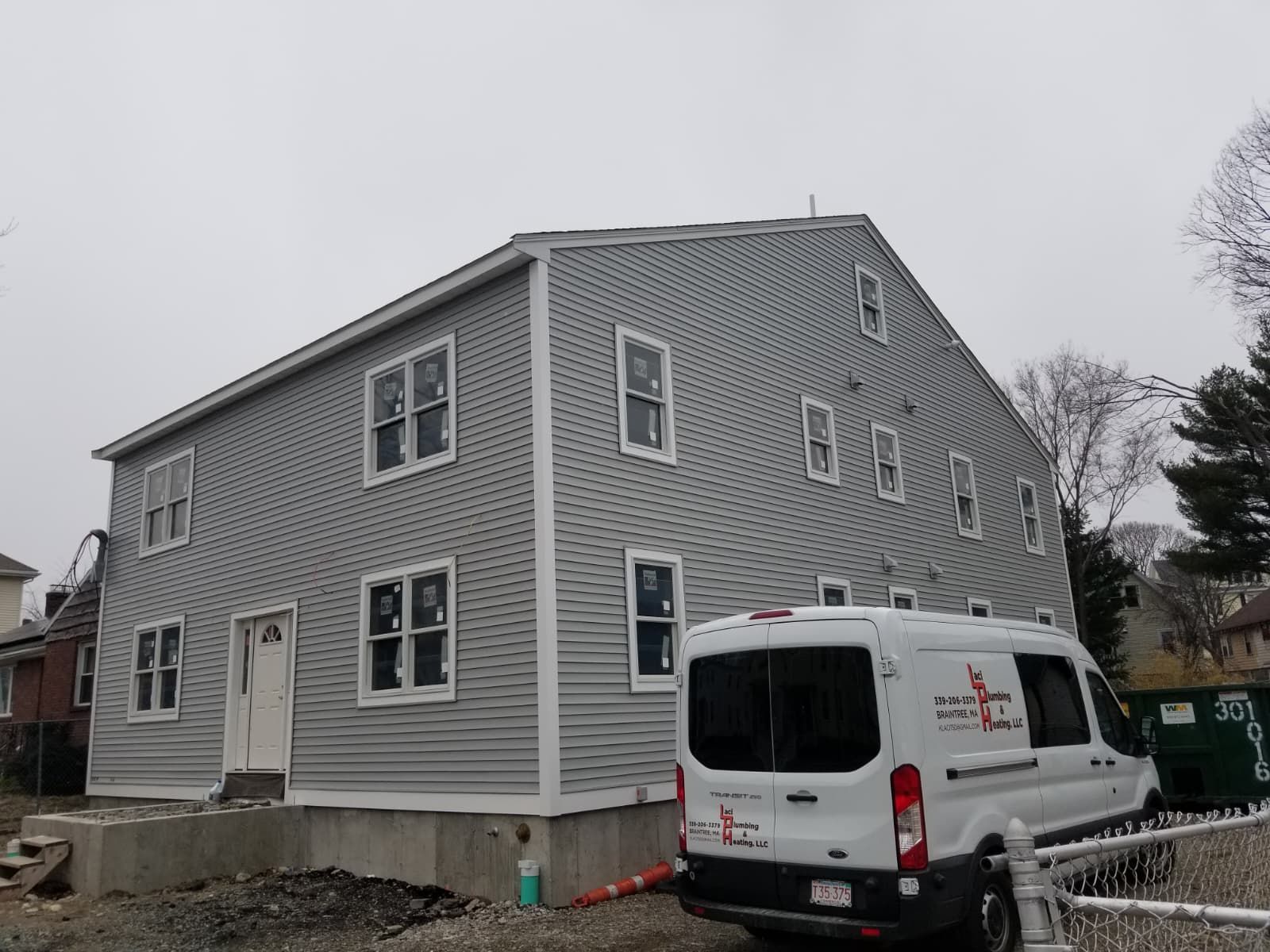 Gray house under construction with white trim and a white service van parked beside it.
