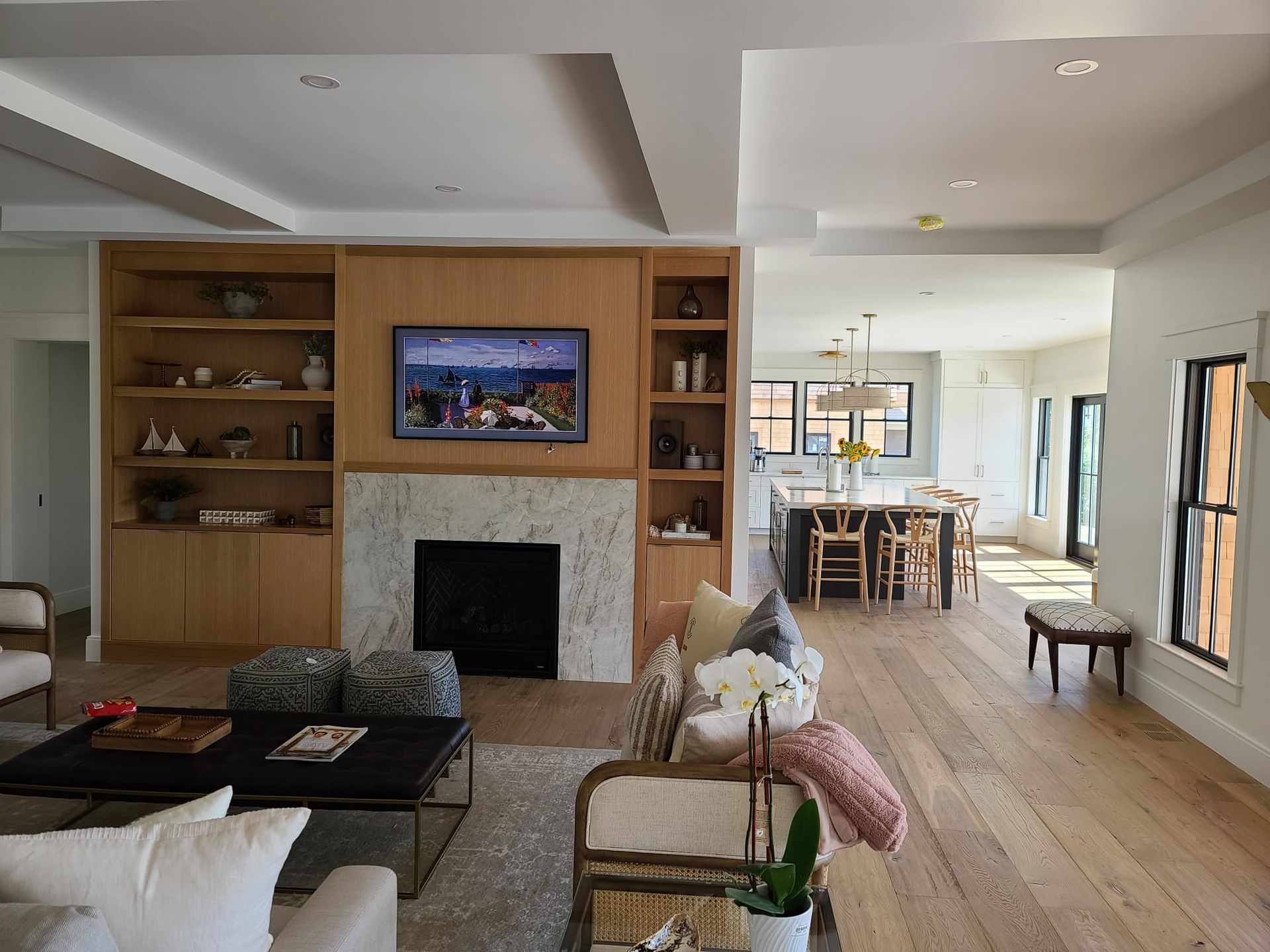 Bright modern living room with fireplace, built-in shelves, sofa, coffee table, and open dining area beyond.