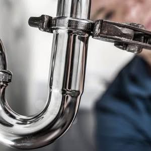 Chrome plumbing pipe under a sink with a clamp and blurred background