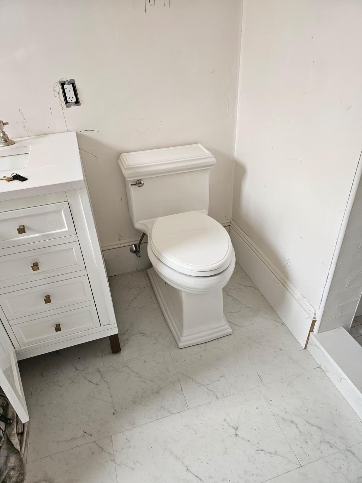 Small white bathroom with a toilet beside a vanity and shower stall.
