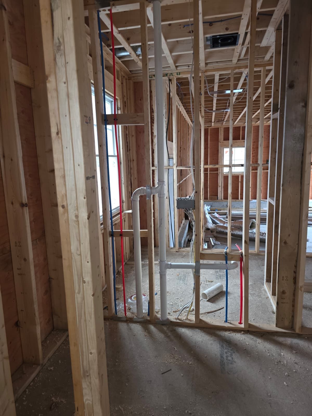 Framed interior of a house under construction with exposed studs, wiring, and unfinished floors