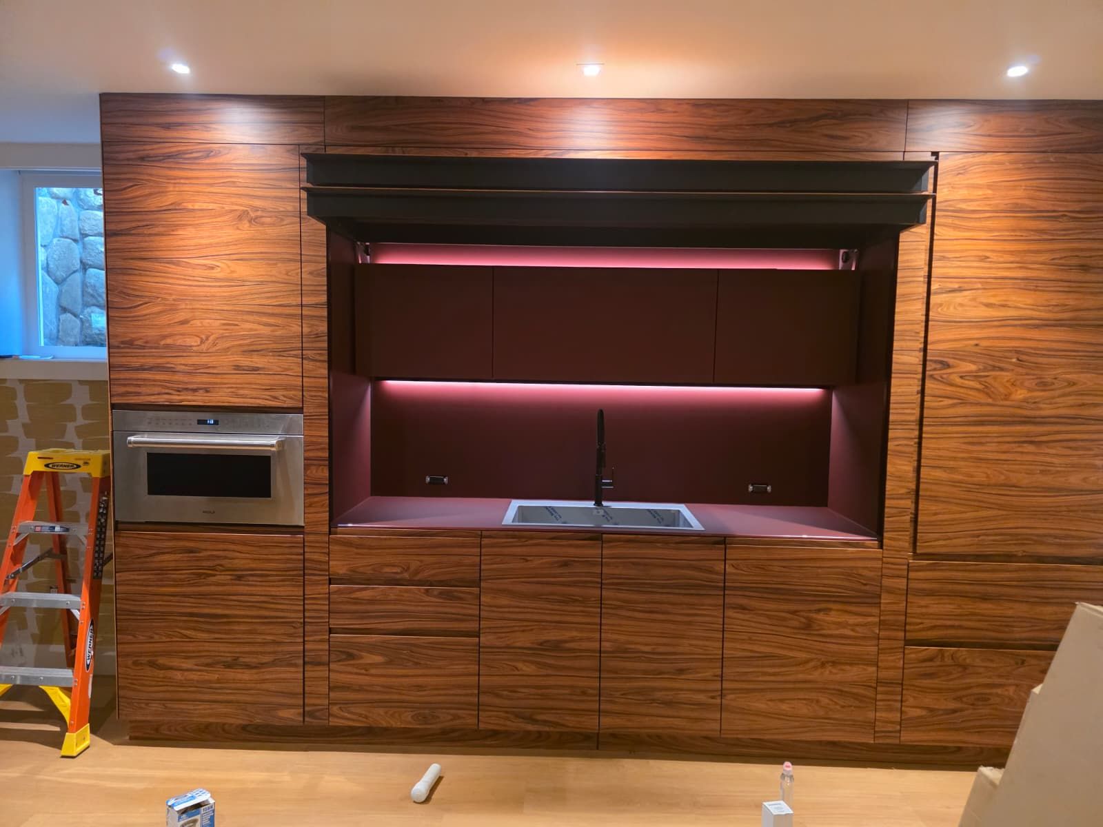 Modern kitchen with wood cabinets, under-cabinet lighting, and a central countertop opening under construction