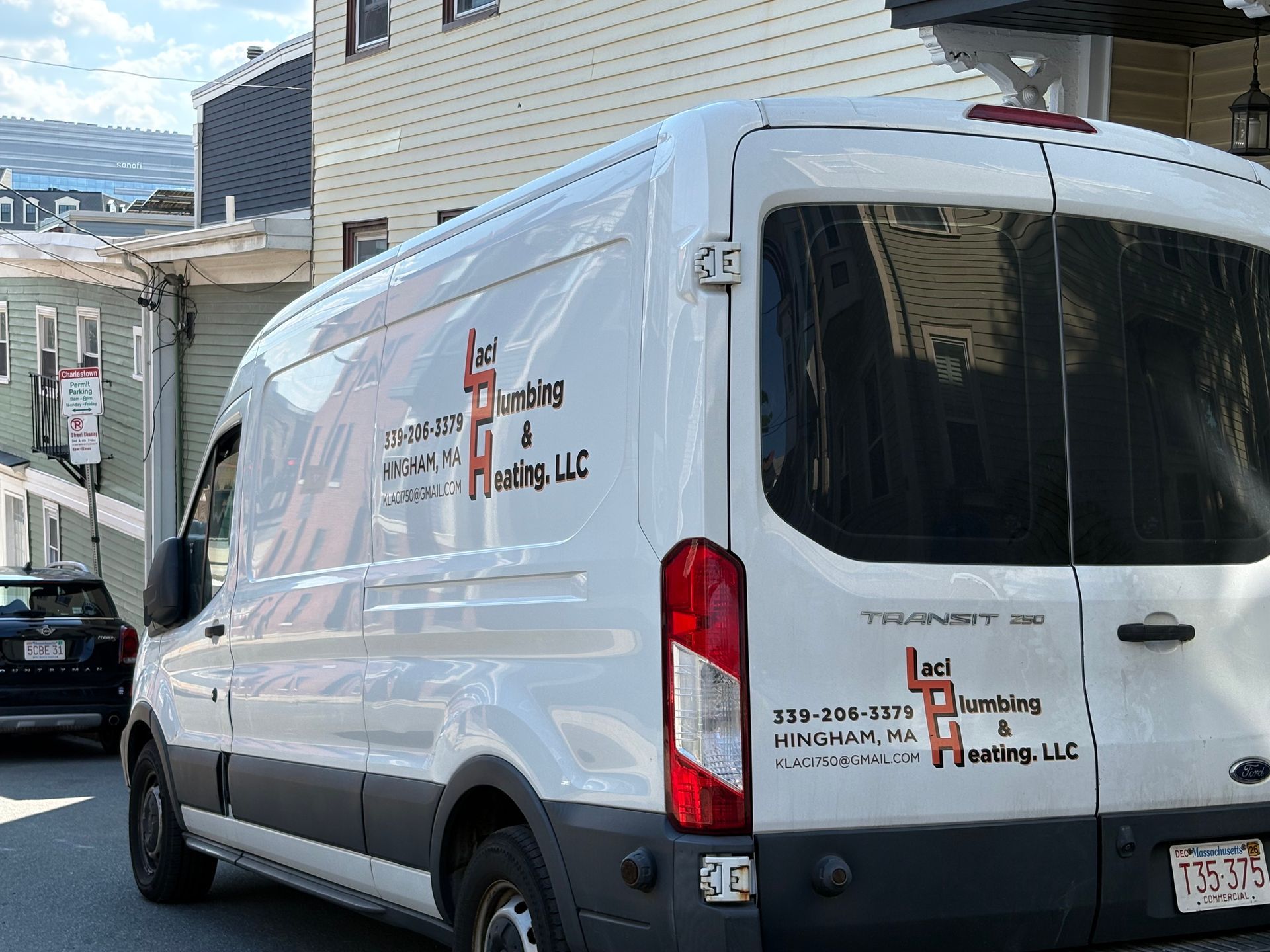 White delivery van parked in a narrow alley beside buildings, rear doors closed.