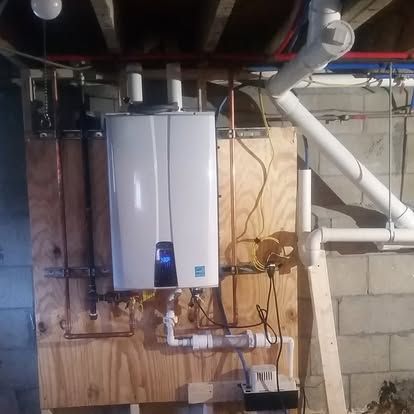 Wall-mounted white boiler with exposed pipes and wiring in an unfinished basement.