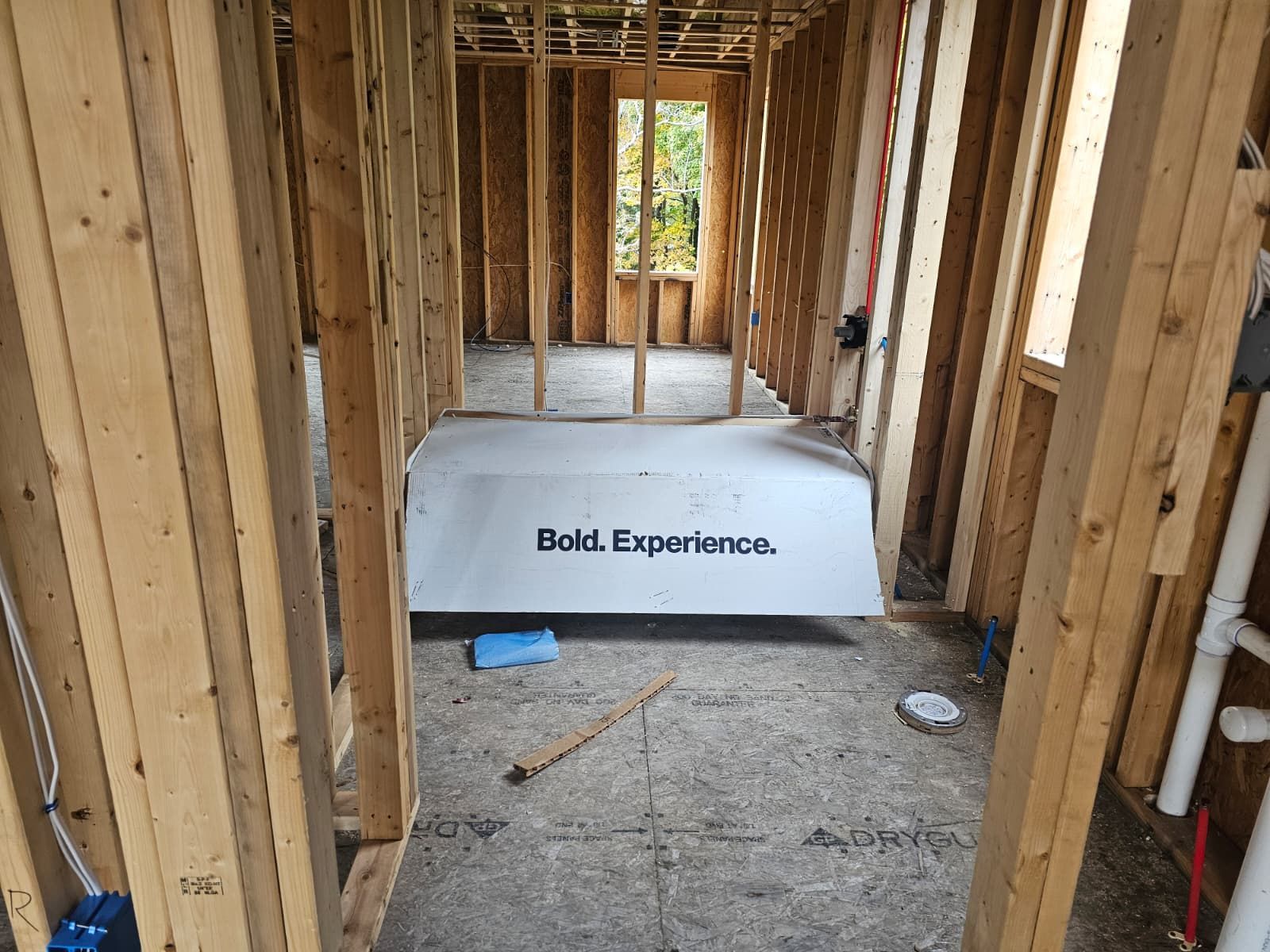 Framed interior under construction with a white panel reading “Bok. Experience.” on the floor.