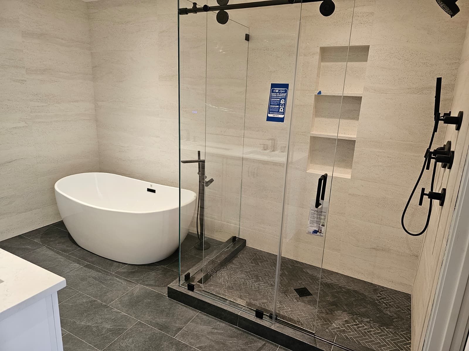 Modern bathroom with freestanding tub, glass shower, dark tile floor, and handheld showerhead