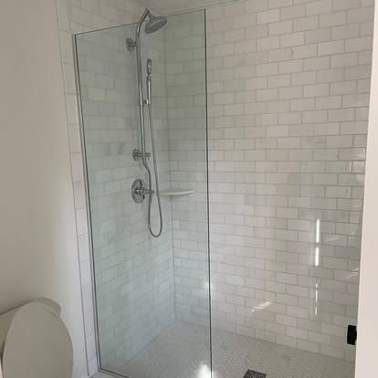 Modern bathroom with glass-enclosed shower and white tile walls