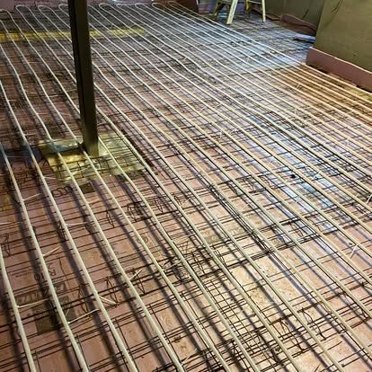 Rebar grid laid over plywood formwork on a construction site, with a vertical support post.