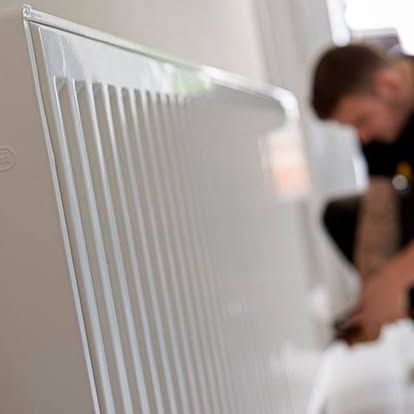 White radiator in foreground with a blurred person working in the background