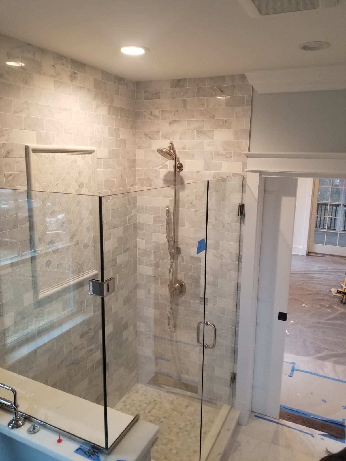 Bathroom shower with glass doors, tile walls, and a freestanding tub under construction.