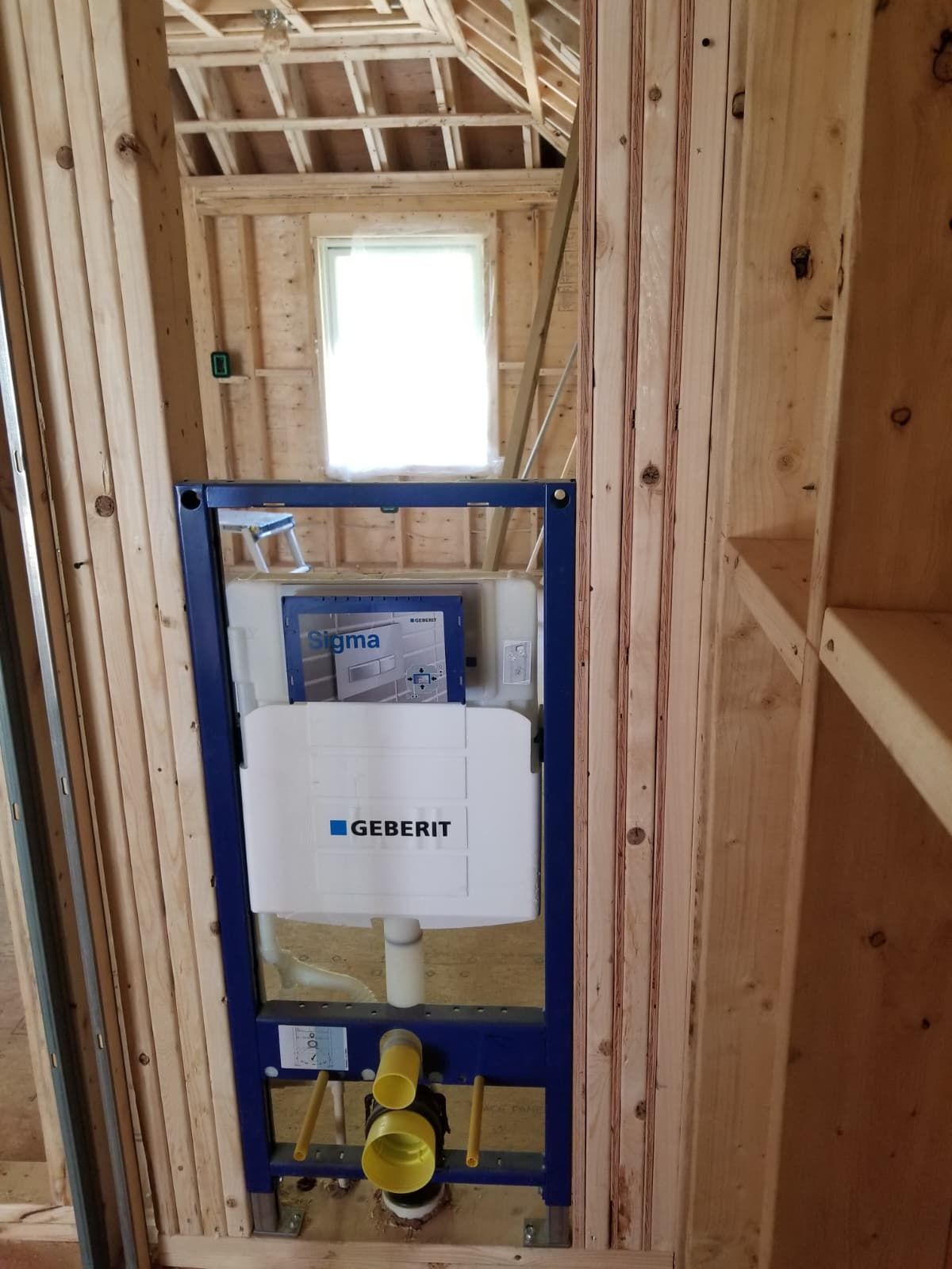 Framed bathroom wall with a blue Gerber toilet support and plumbing inside an unfinished space