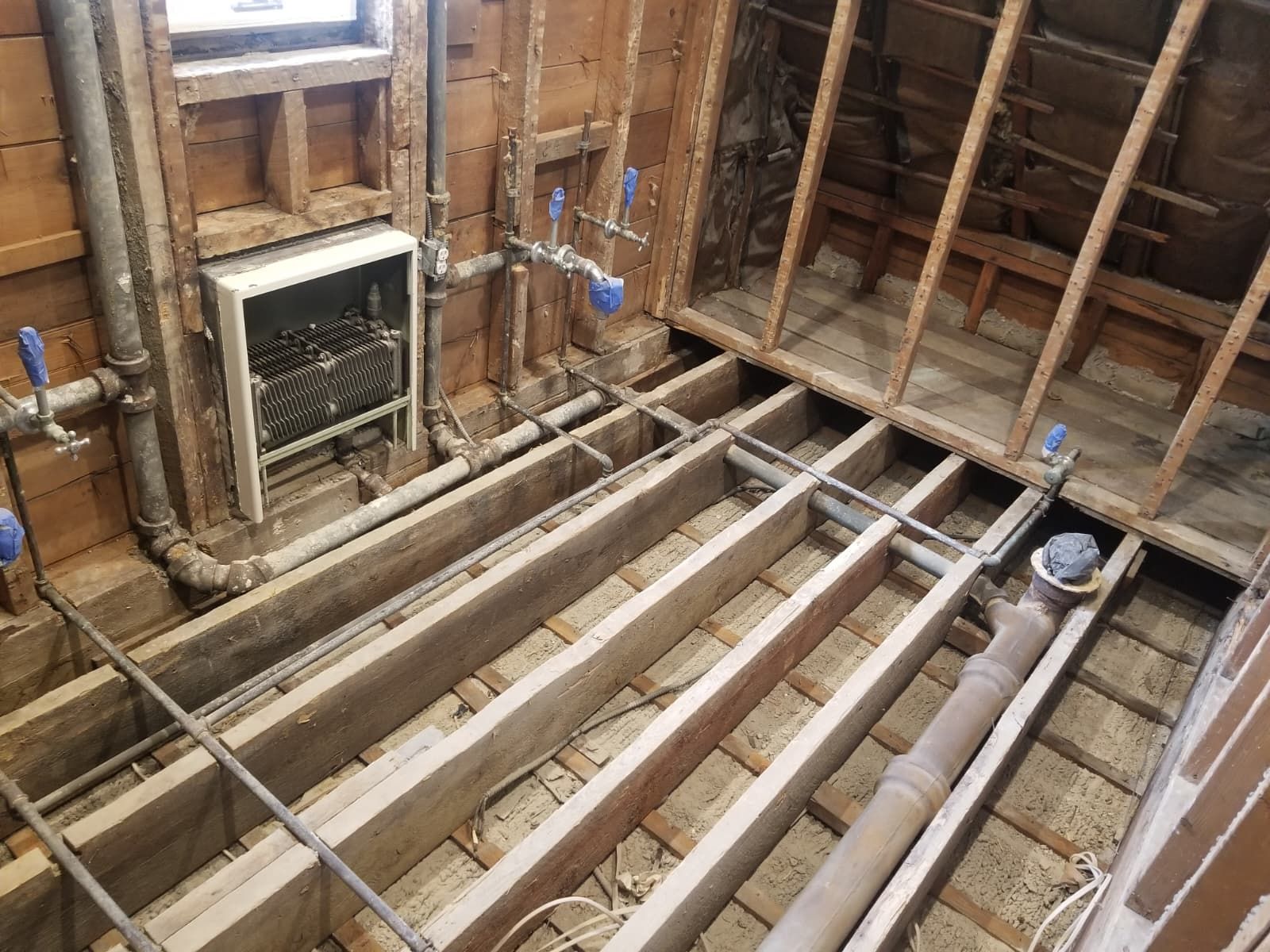 Unfinished room with exposed floor joists, insulation, and a small fireplace framed in wood studs