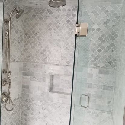 Glass shower with chrome fixtures and frosted patterned tile walls