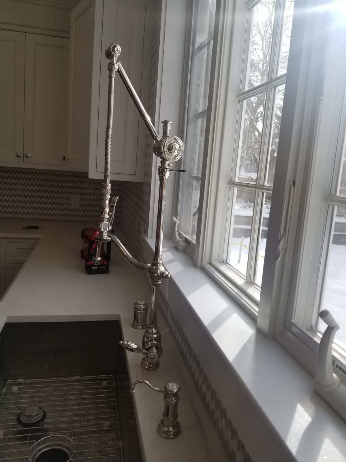 Kitchen sink by a bright window with a tall chrome faucet and soap dispenser