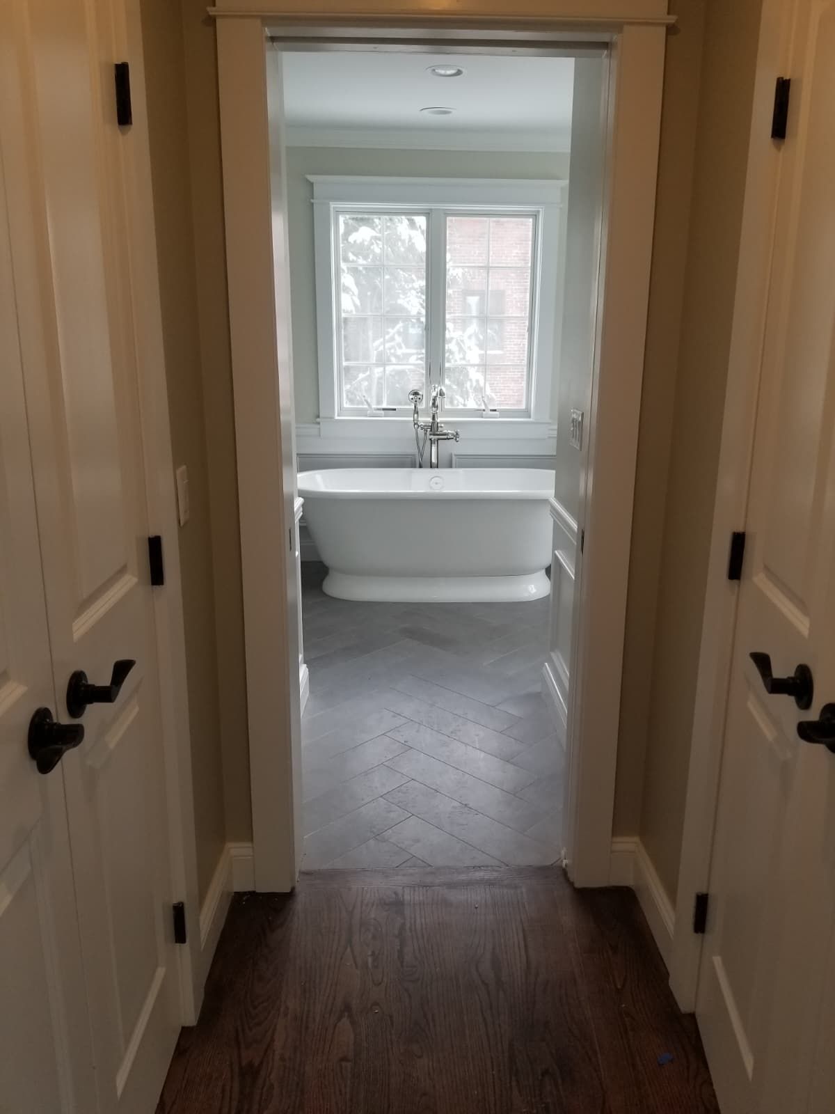 Hallway leading to a bright bathroom with a freestanding tub and window