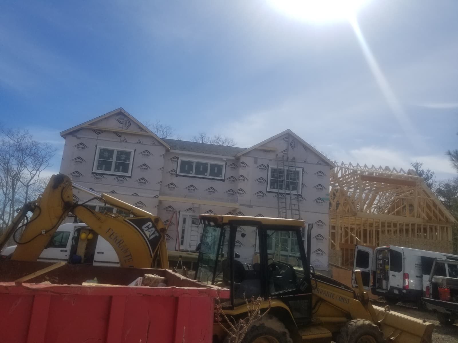 Construction site with excavators and a house under construction on a sunny day