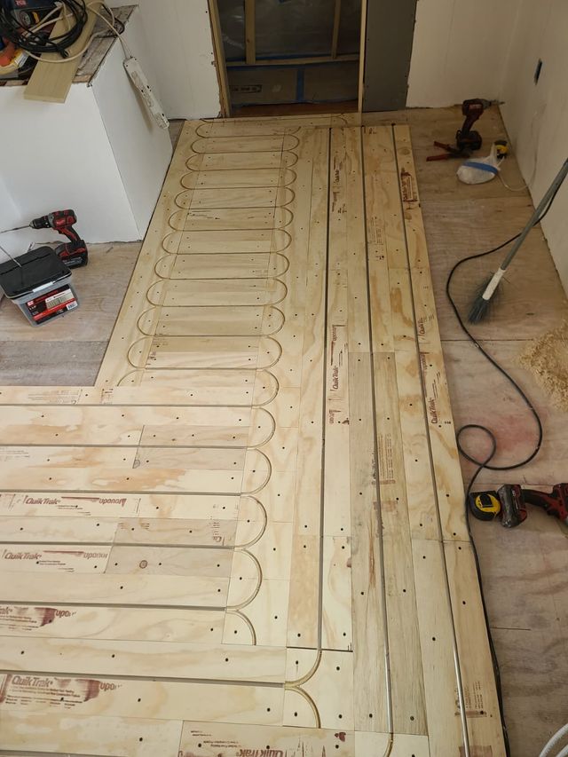 Partially installed wooden floor subfloor with tools in a room under renovation