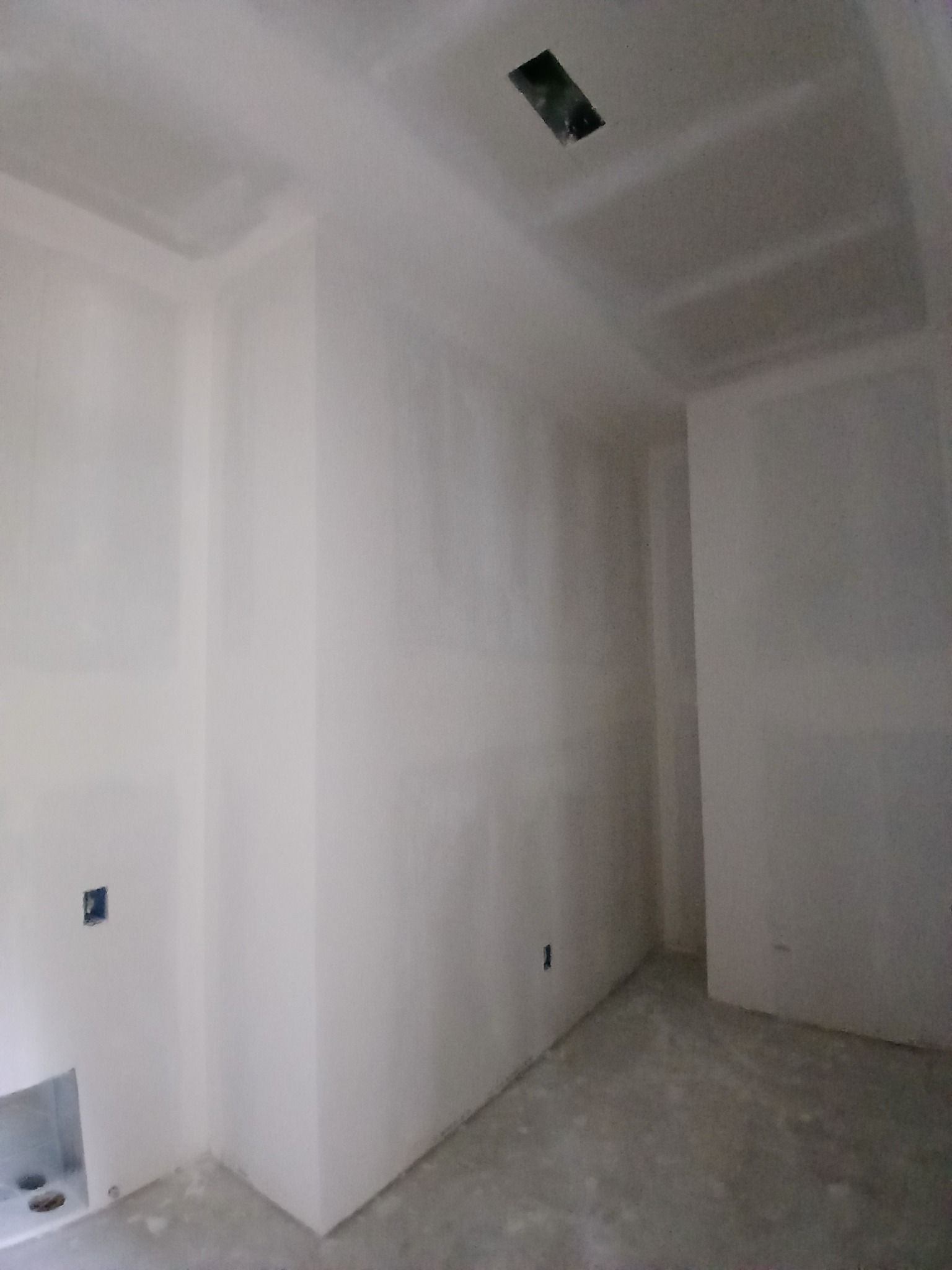 Unfinished room with drywall walls and ceiling, electrical outlets, and concrete floor.