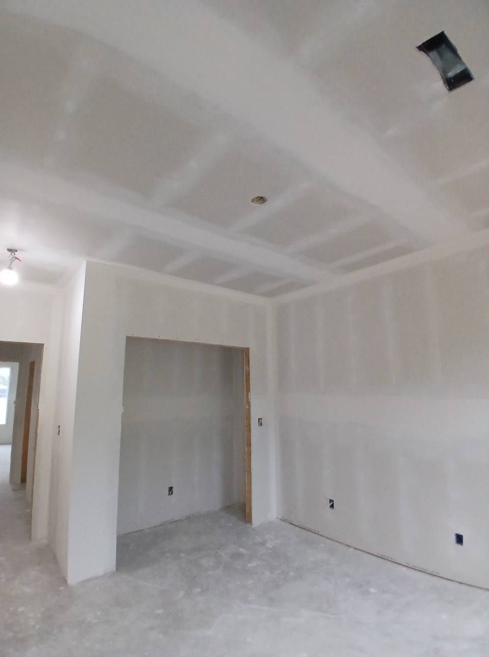 Interior room under construction, with drywall on walls and ceiling.