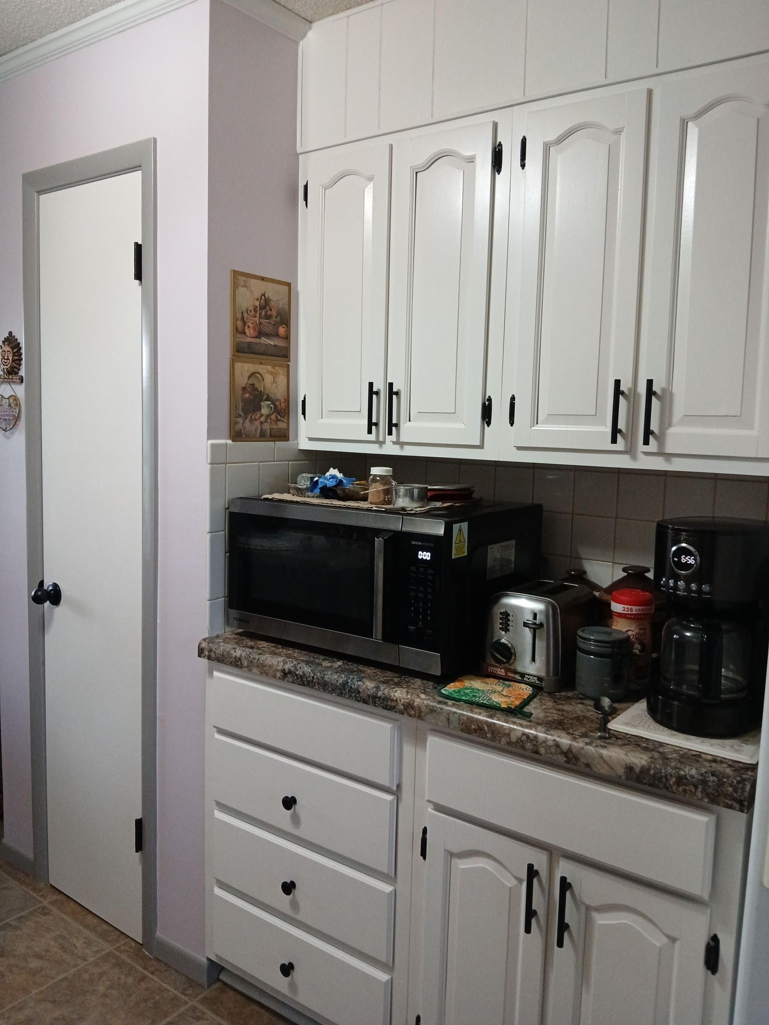 White kitchen cabinets and appliances; microwave, toaster, and coffee maker on counter.