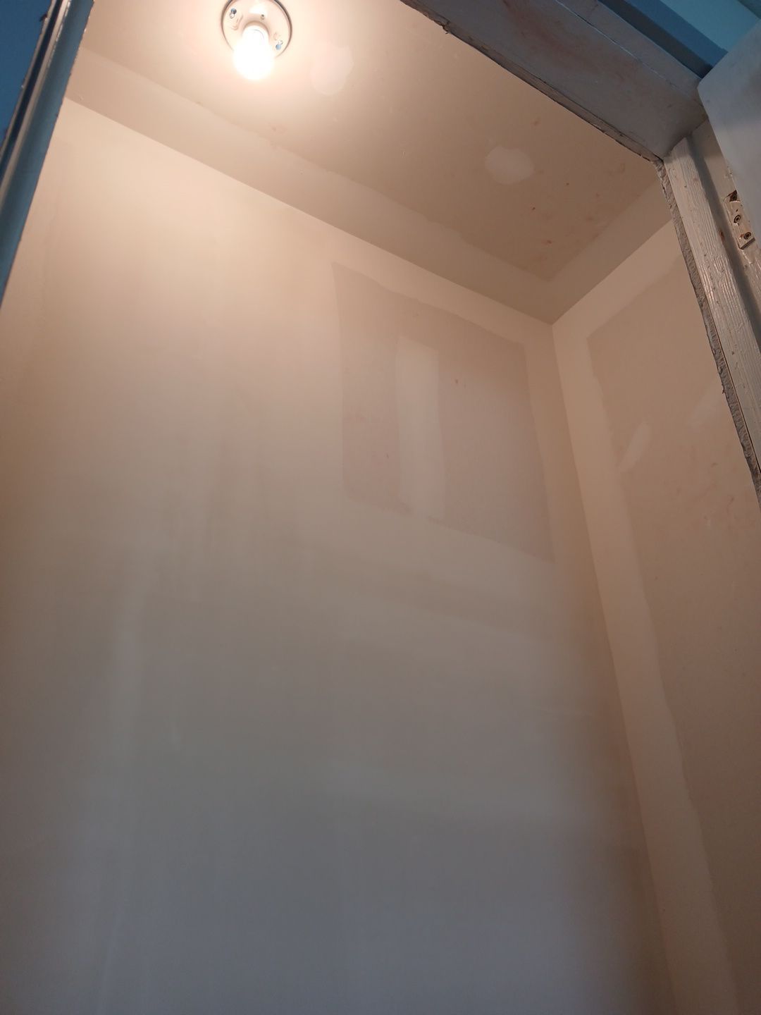 Interior view of a light-colored, unfinished closet, with a single overhead light.