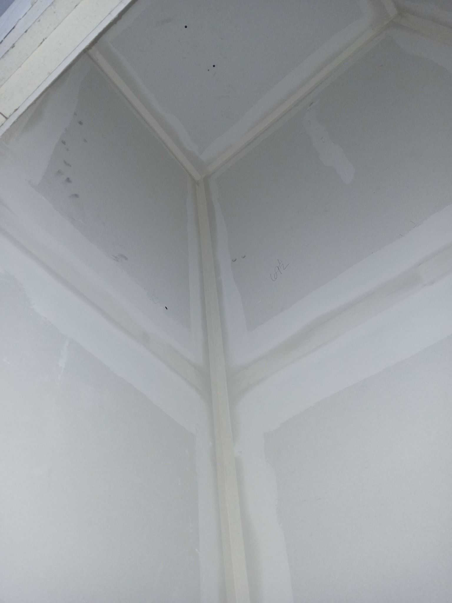 Interior corner of a room with taped drywall seams, ready for paint.
