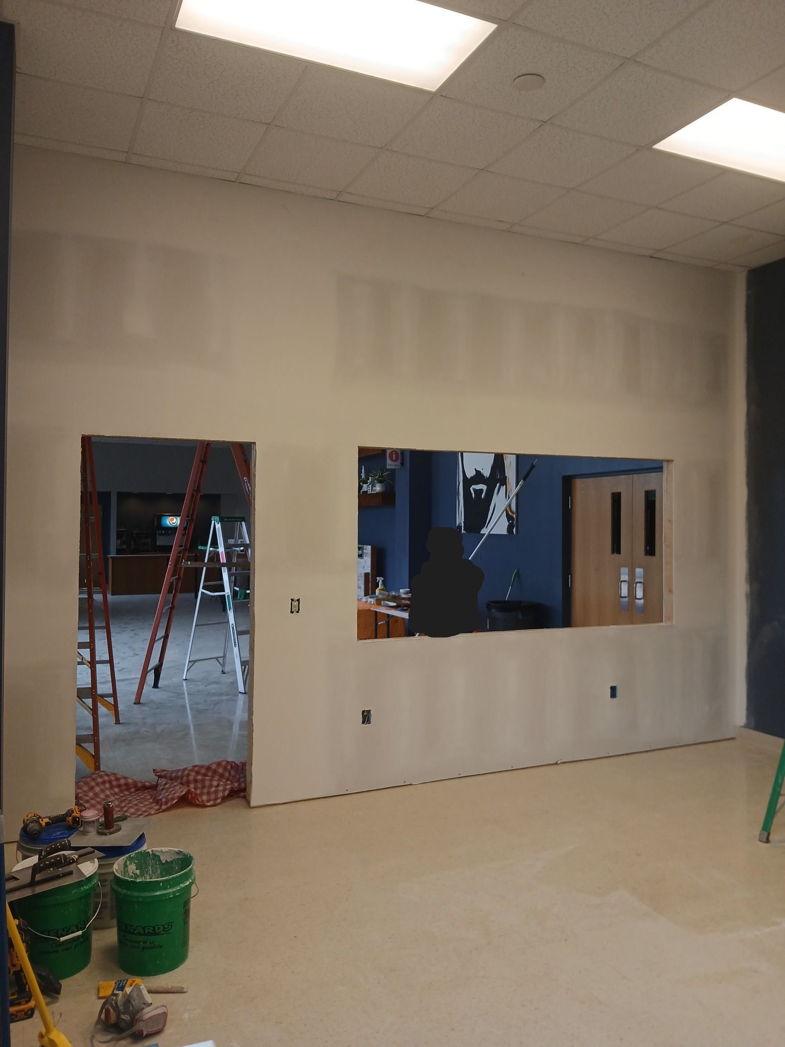Interior under construction with unfinished walls, a doorway, and a window. A ladder is visible.