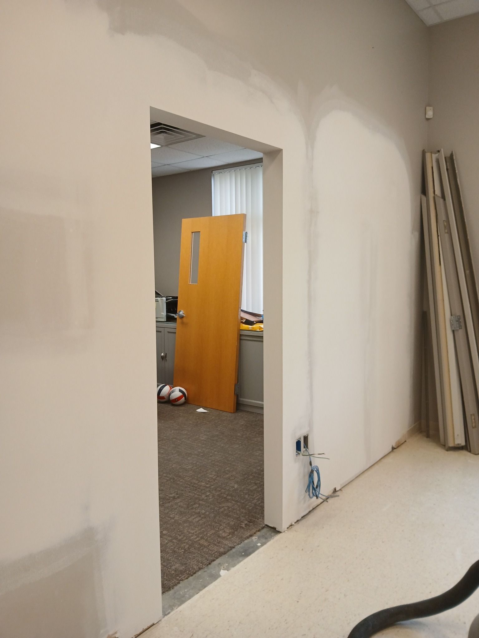 Room doorway with drywall work in progress. Beige walls, brown door visible.