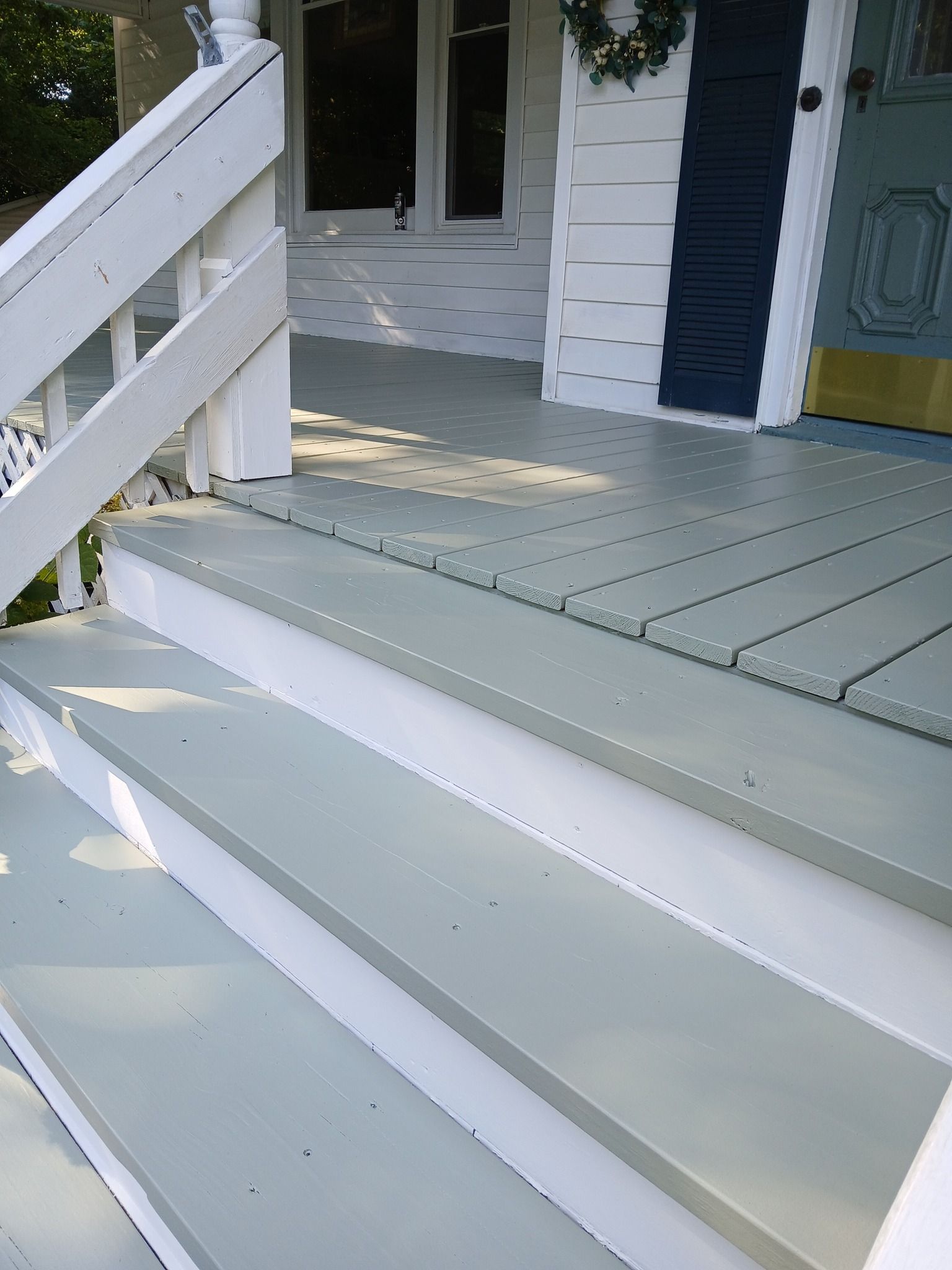 Light gray painted porch steps leading to a white and blue painted entrance.