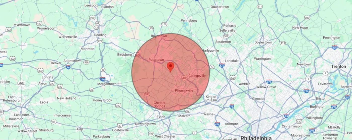 Map with a red circular area marked near the center and a red pin on a light green road map.