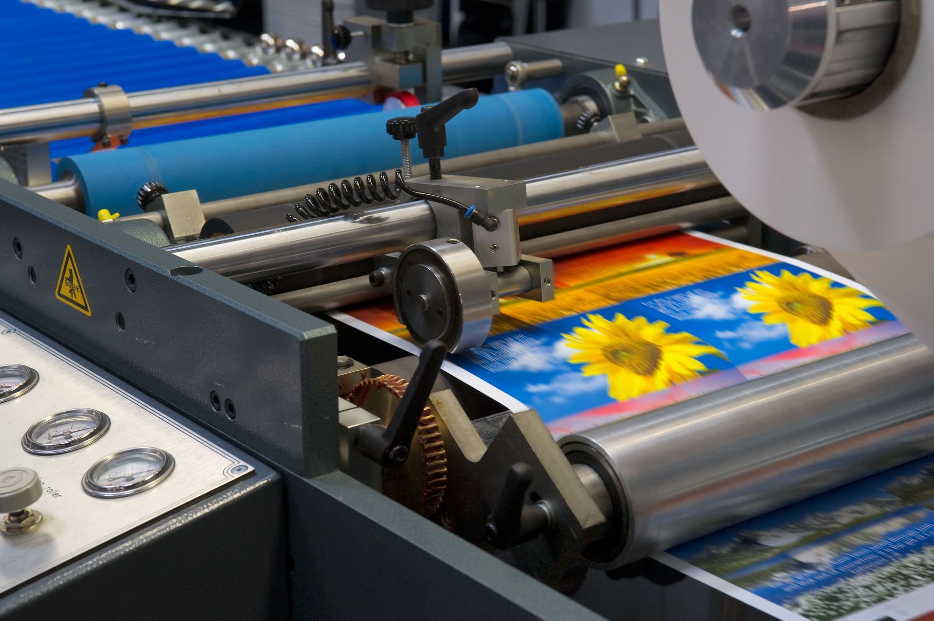 Printing machine producing colorful sunflower posters on a roller press