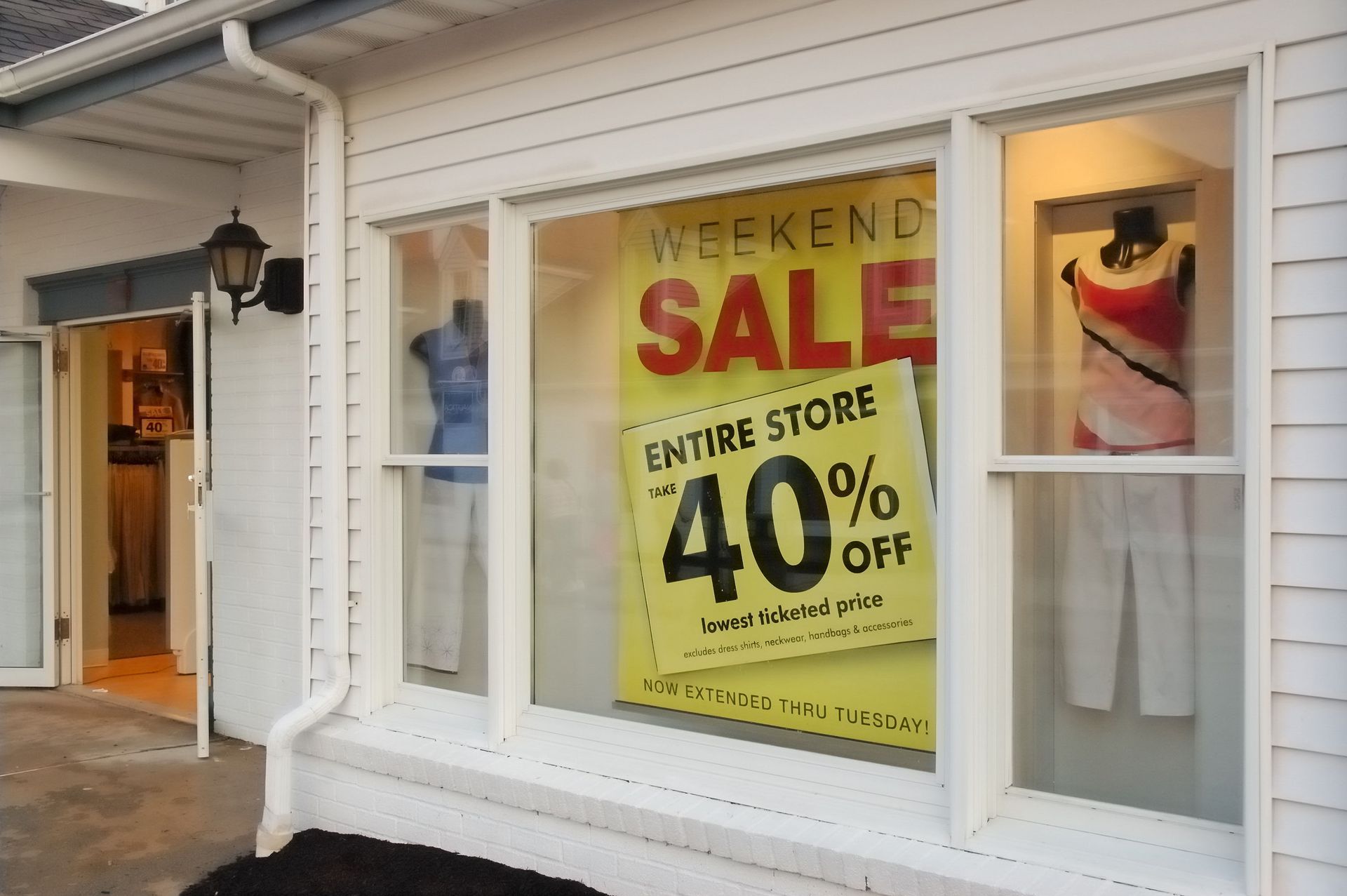 Storefront window sale sign reading “Weekend Sale” and “40% off” in a beige shopping plaza