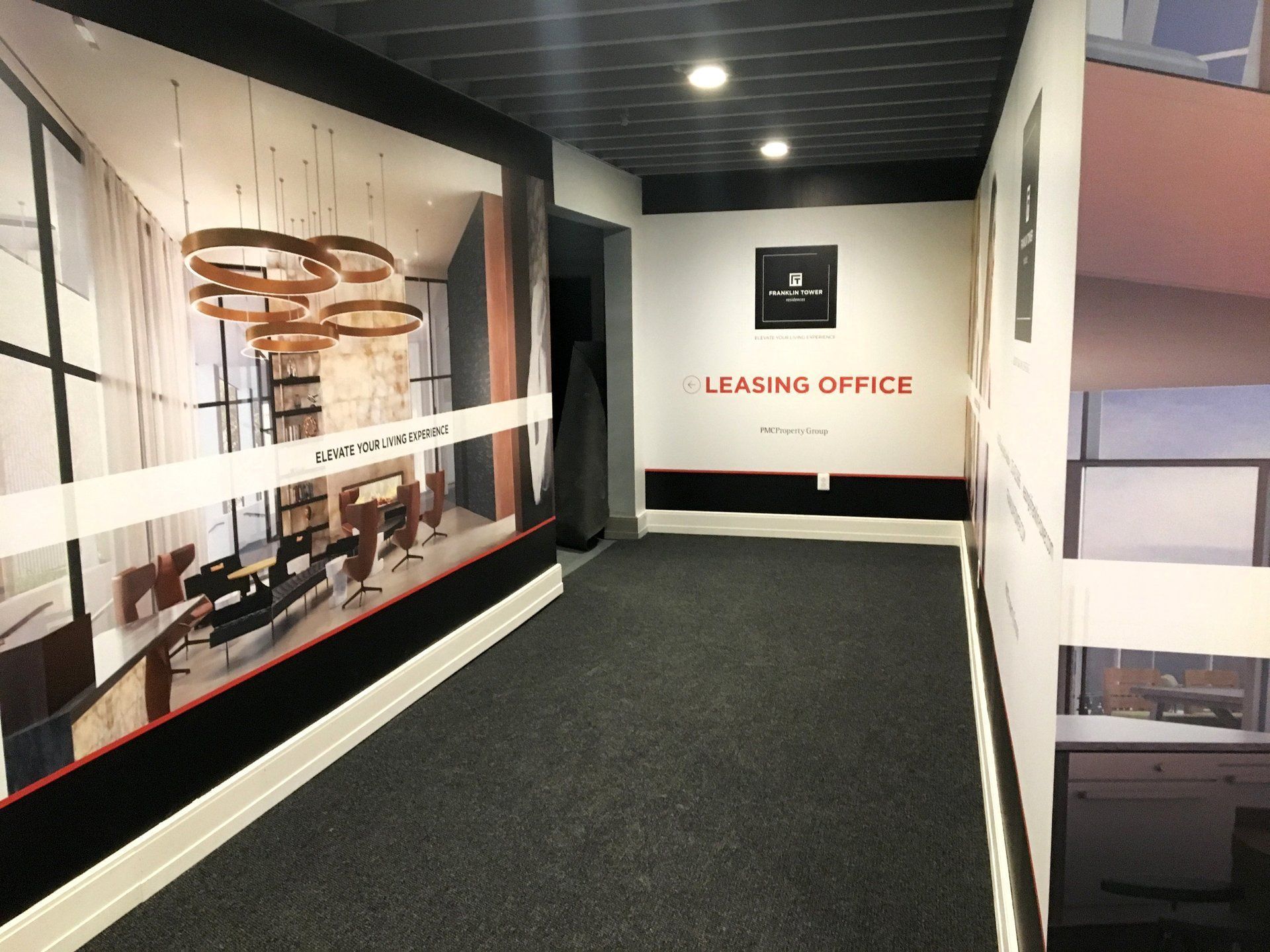 Empty office hallway with carpeted floor, ceiling lights, and a “Leasing Office” sign ahead.