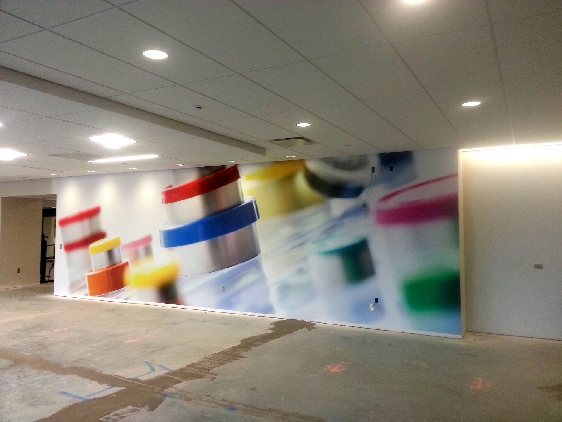 Blurred colorful abstract mural on a wall in a bright indoor hallway with ceiling lights