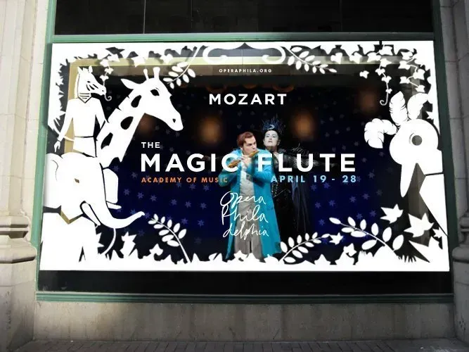 The Magic Flute poster by Mozart, black and white with blue accents, in a window display
