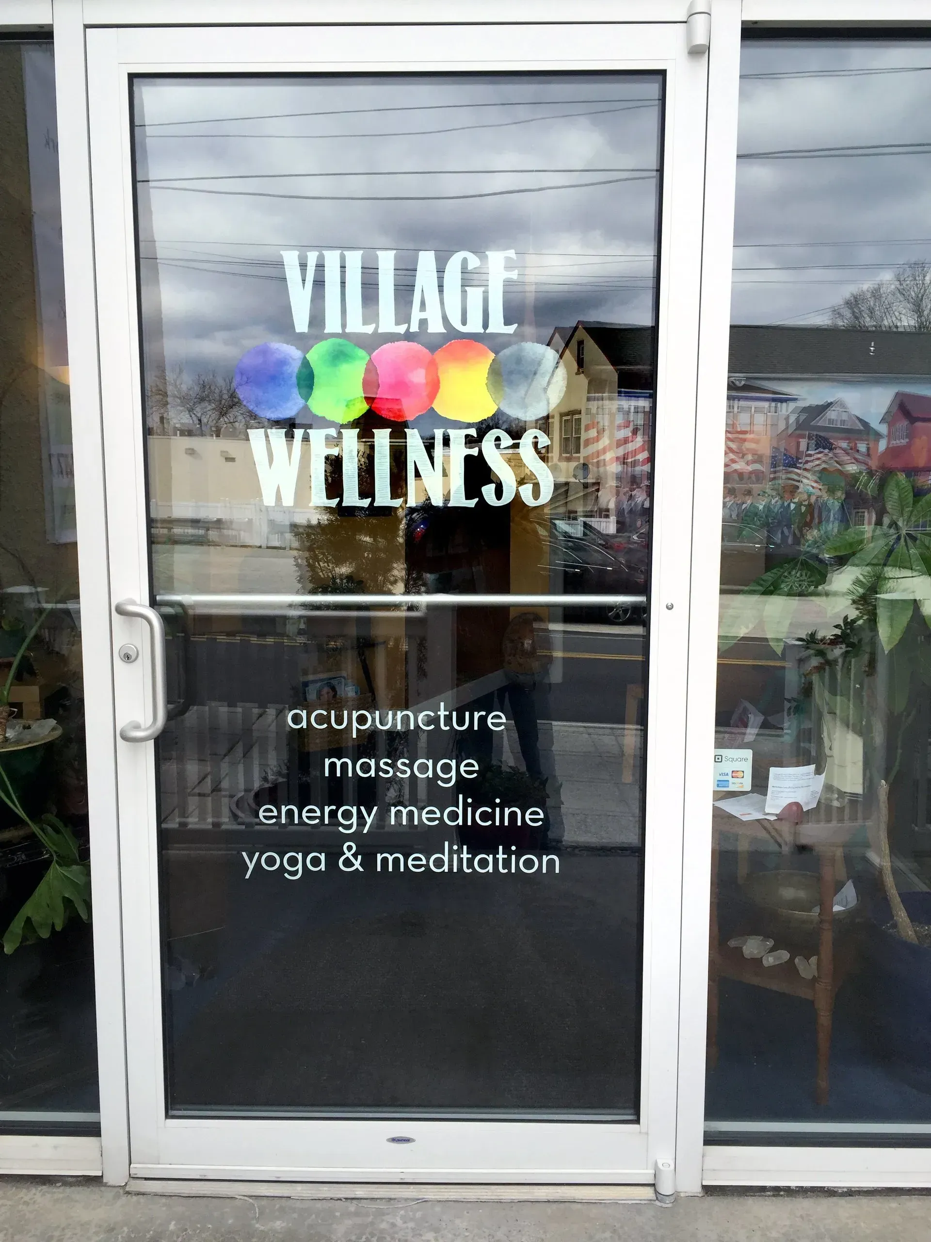 Storefront window for Village Wellness, with acupuncture, massage, energy medicine, yoga, and meditation services.