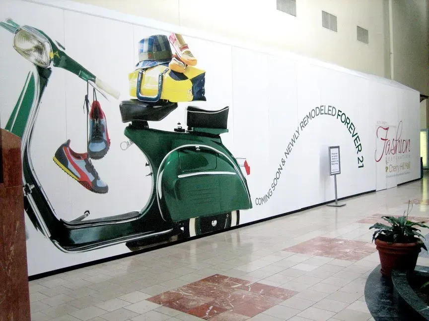 Large indoor mural of a green scooter with luggage in a tiled hallway